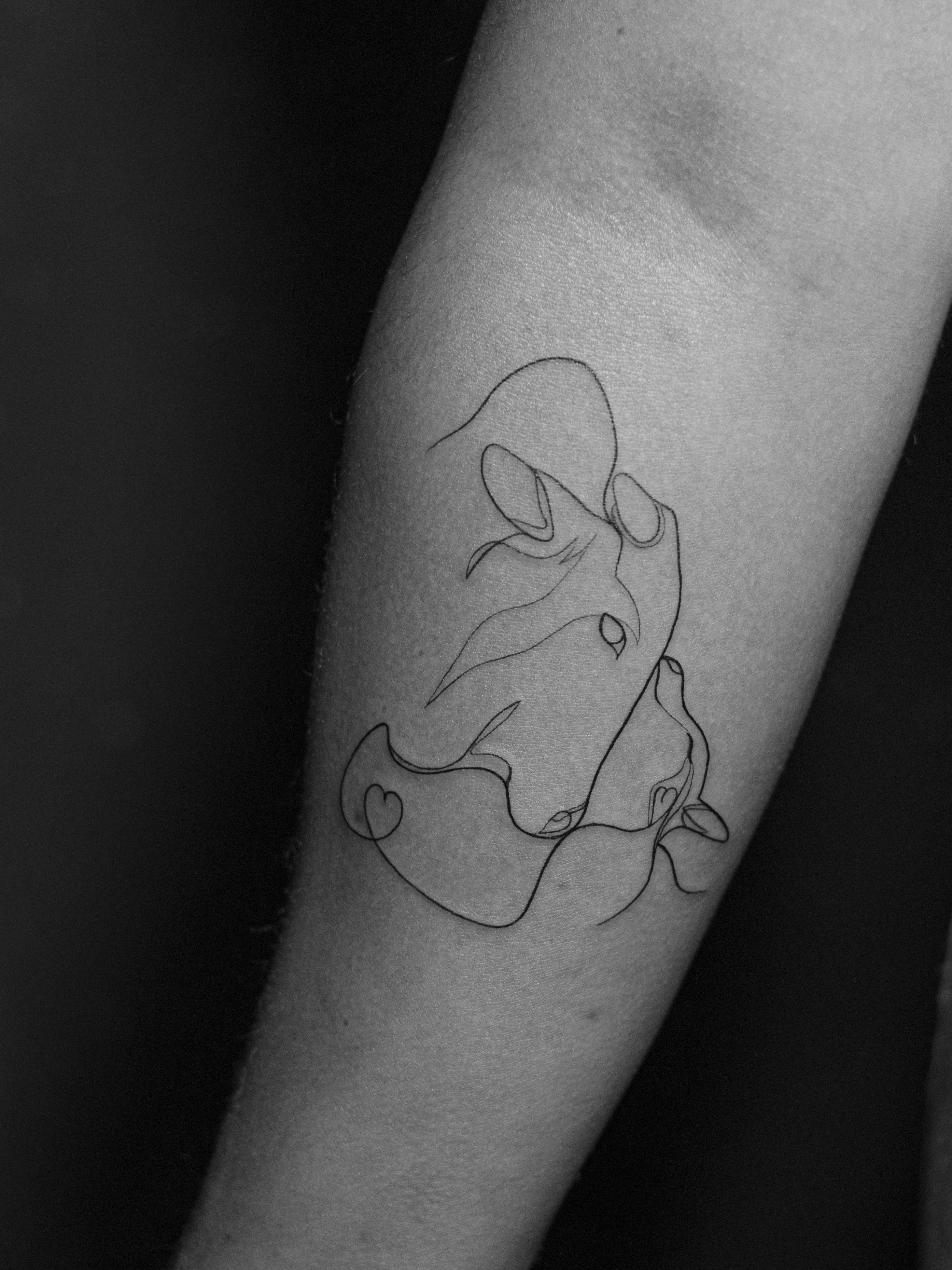 Minimalist tattoo made in fineline, continuous line style (oneline) on the forearm area, representing a cow and its calf.