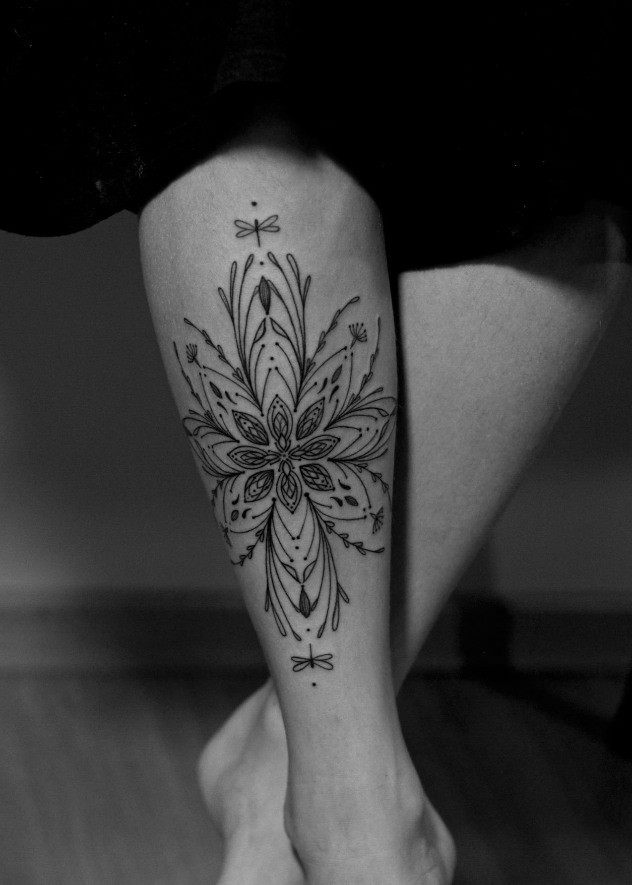 Minimalist tattoo made in fineline on the tibia area, representing a mandala.