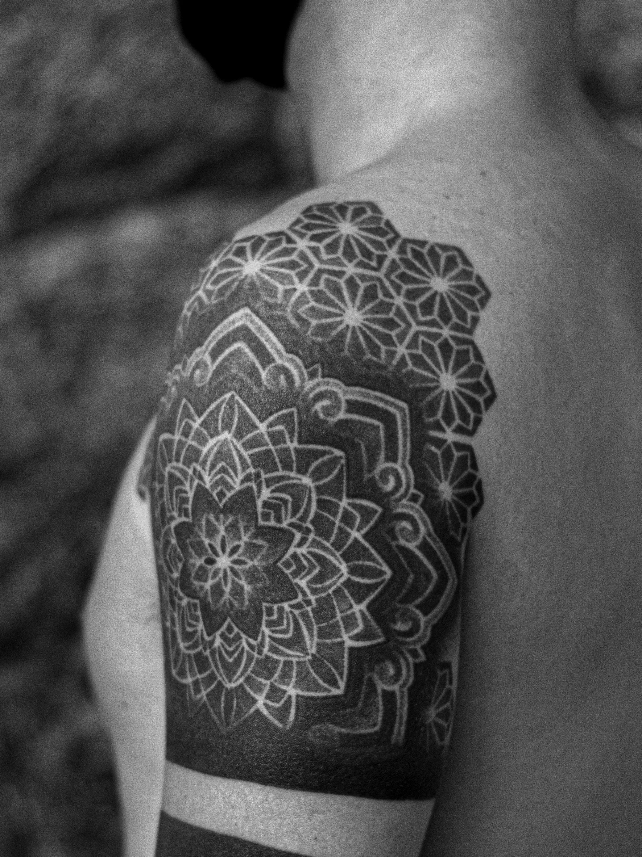 Tattoo made in dotwork on the shoulder and arm area, representing a flower/mandala and geometric patterns.