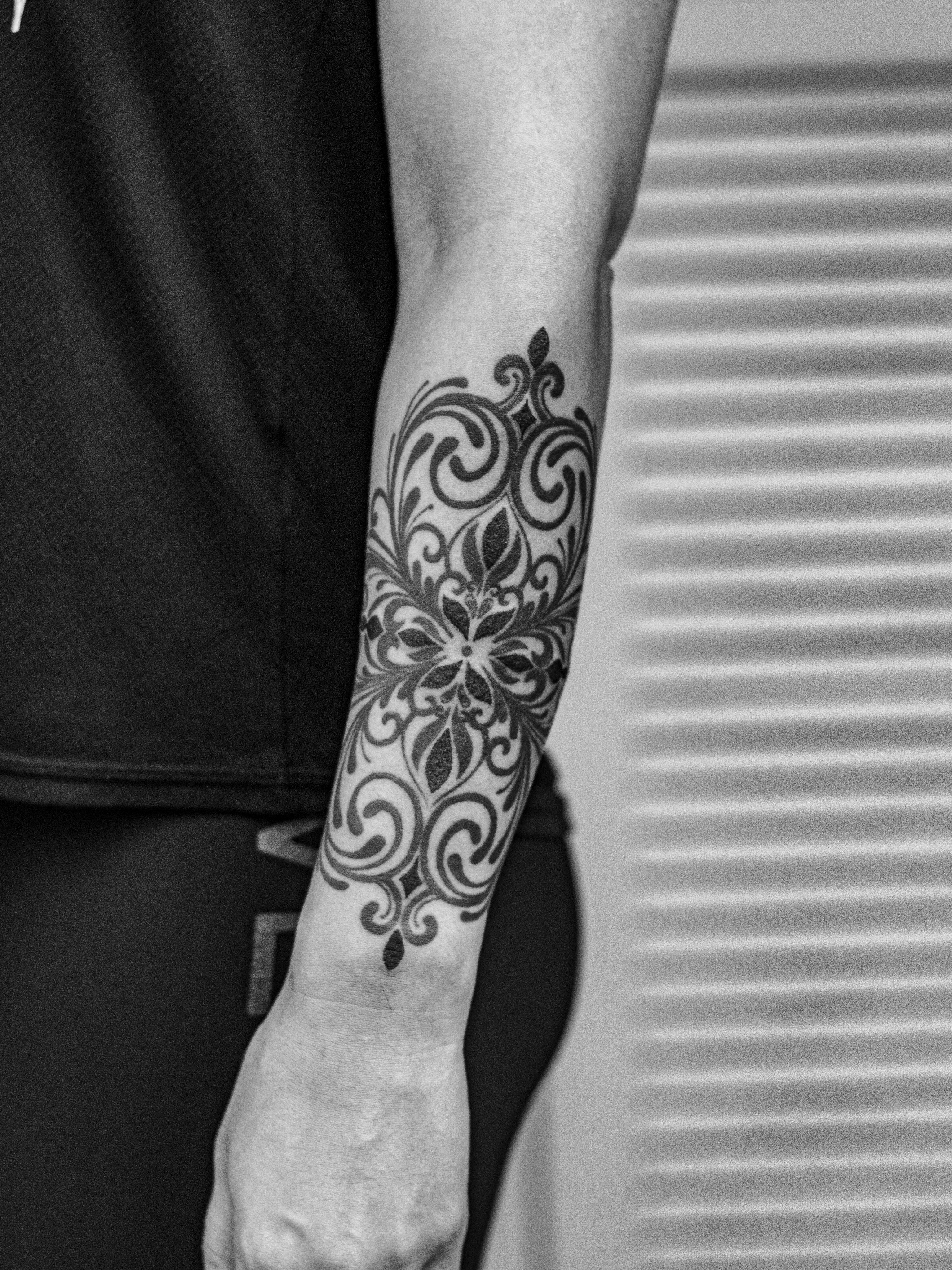 Ornamental tattoo made in dotwork, only in black (blackwork), on the forearm area, representing ornaments and mandala flowers.