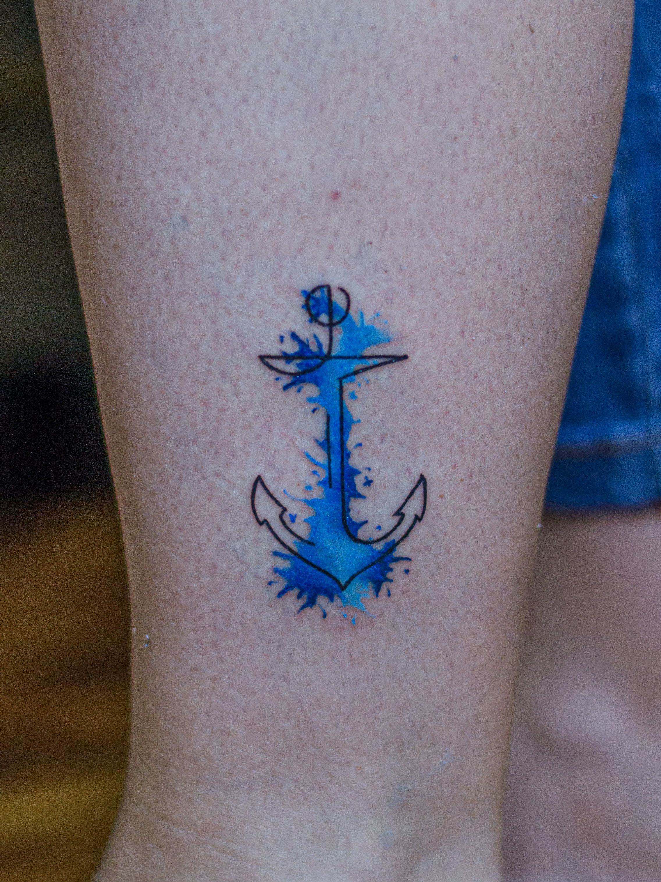 Minimalist tattoo made in fineline, colored watercolor style, representing an anchor.