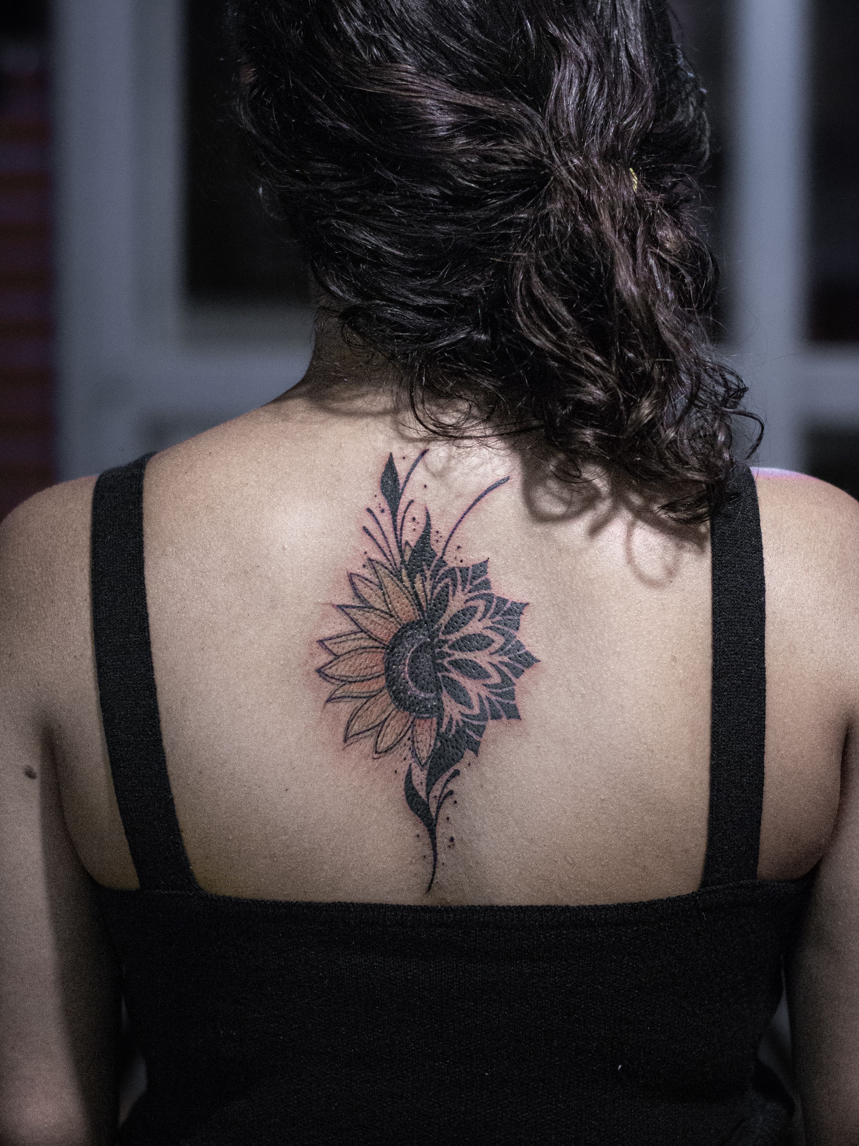 Tattoo made in fineline, colored, sketch style, representing half a sunflower and half a mandala in dotwork.