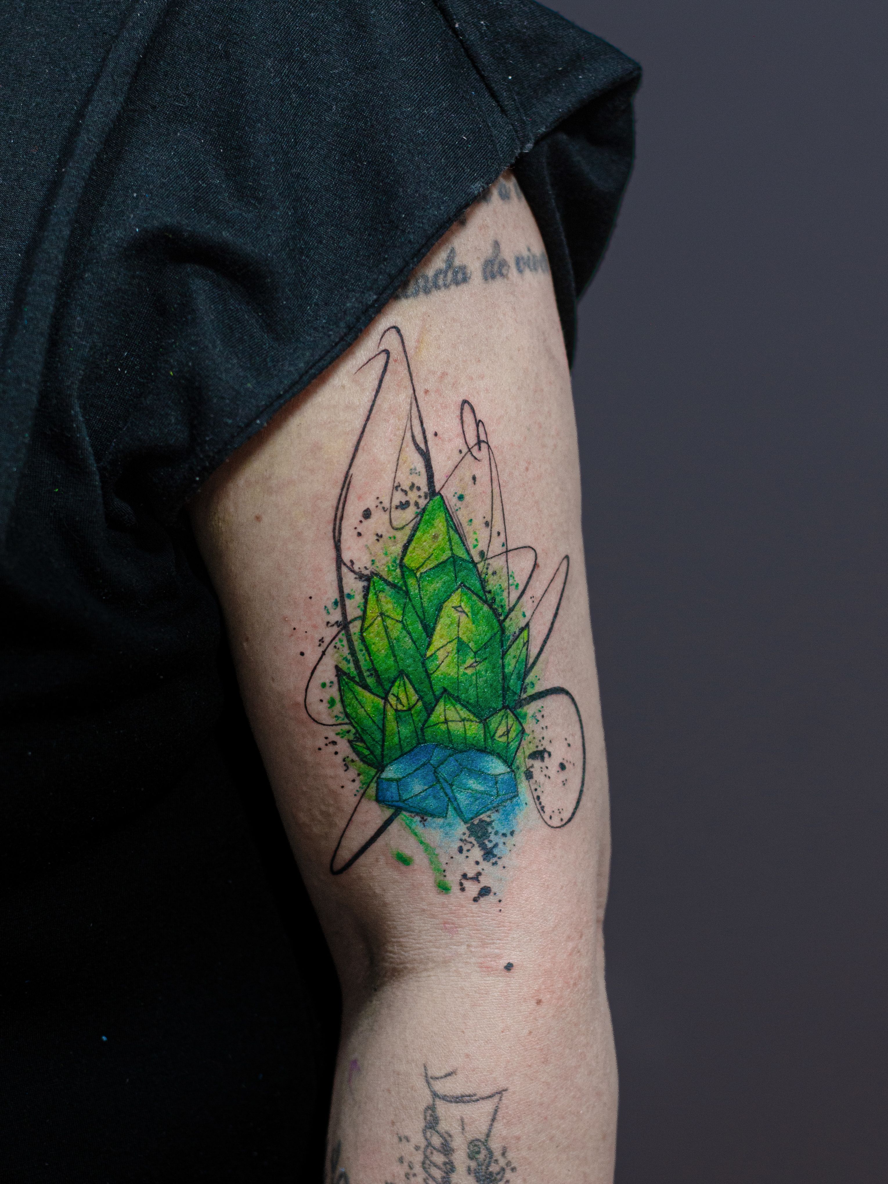Minimalist tattoo made in fineline, colored watercolor style, sketch style, representing three emerald stones and two diamond stones.