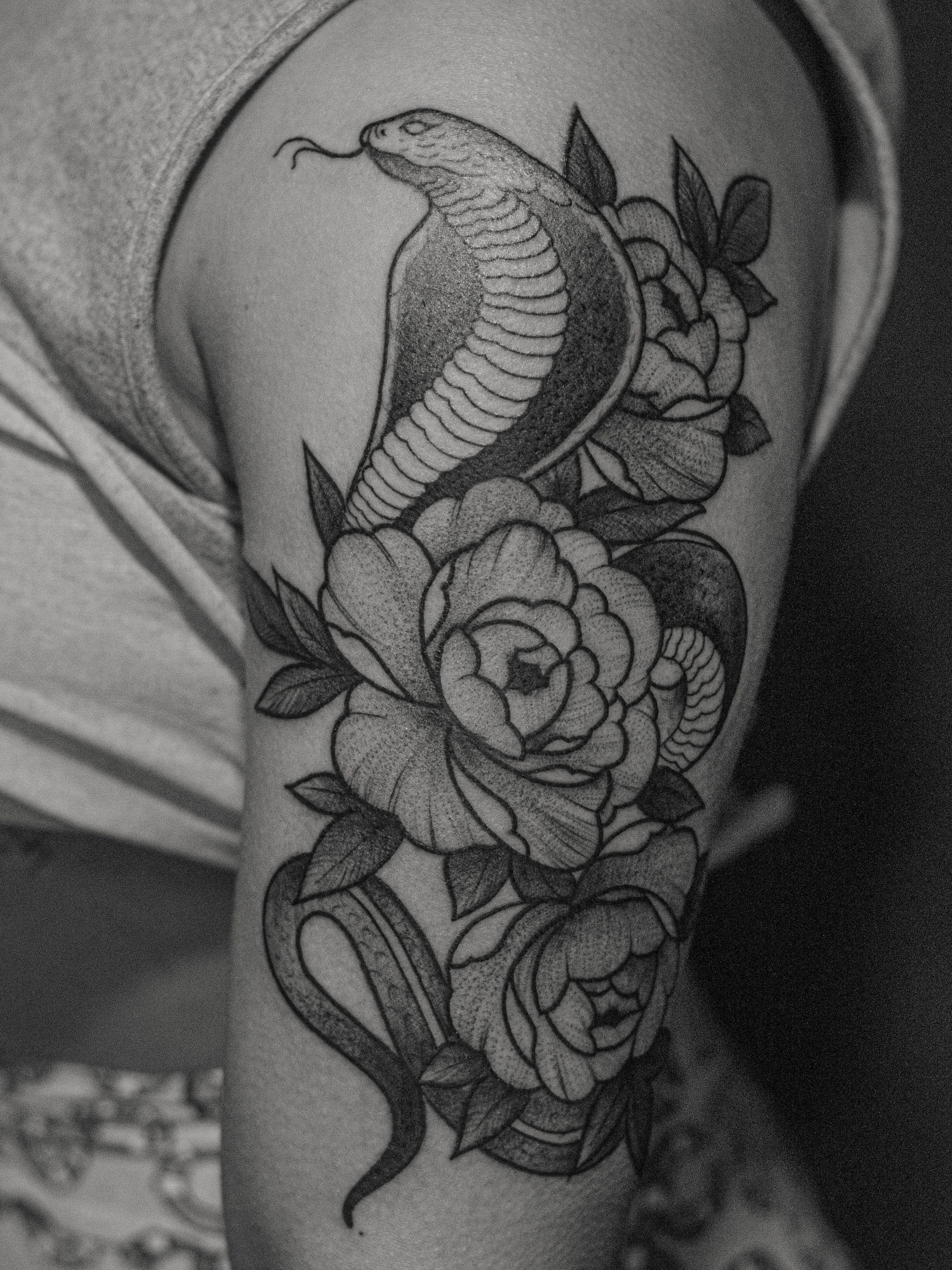 Tattoo made in fineline, only in black (blackwork), on the arm area, representing a snake and flowers.